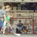 Mother playing hockey in garage with two sons